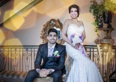 A bride and groom posing in front of a staircase.